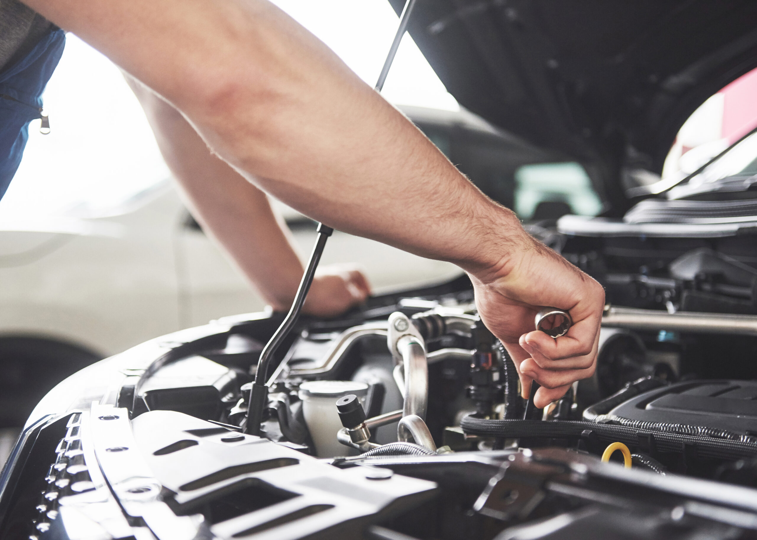 Auto mechanic working in garage. Repair service Close up hands of unrecognizable mechanic doing car service and maintenance.